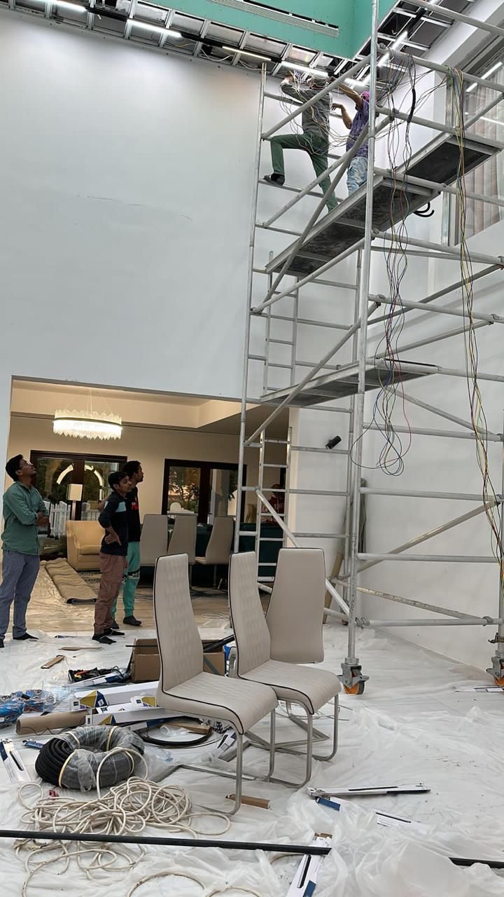 Electricians on a scaffold tower wiring a double-height ceiling